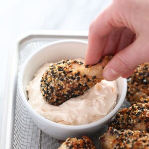 a person dipping crispy baked chicken wings in a bowl.