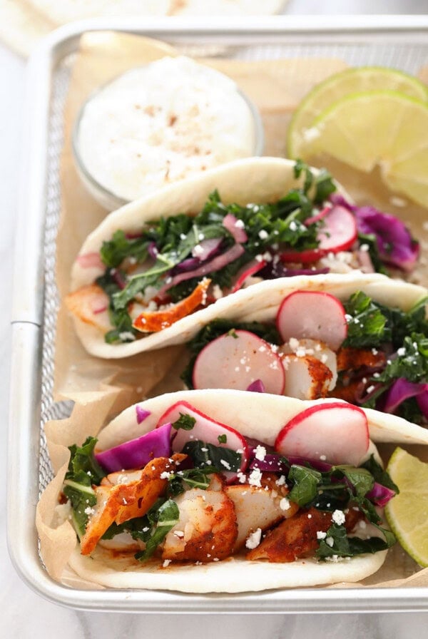 Fish tacos with slaw and sour cream served on a tray.