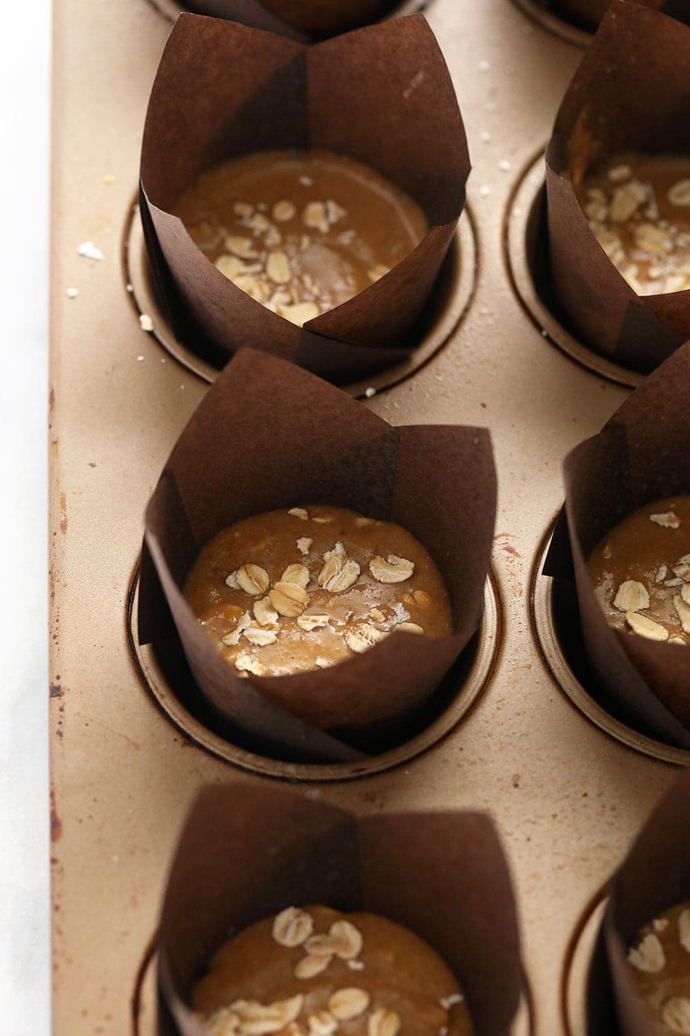 classic oatmeal muffins in a muffin pan ready to be baked