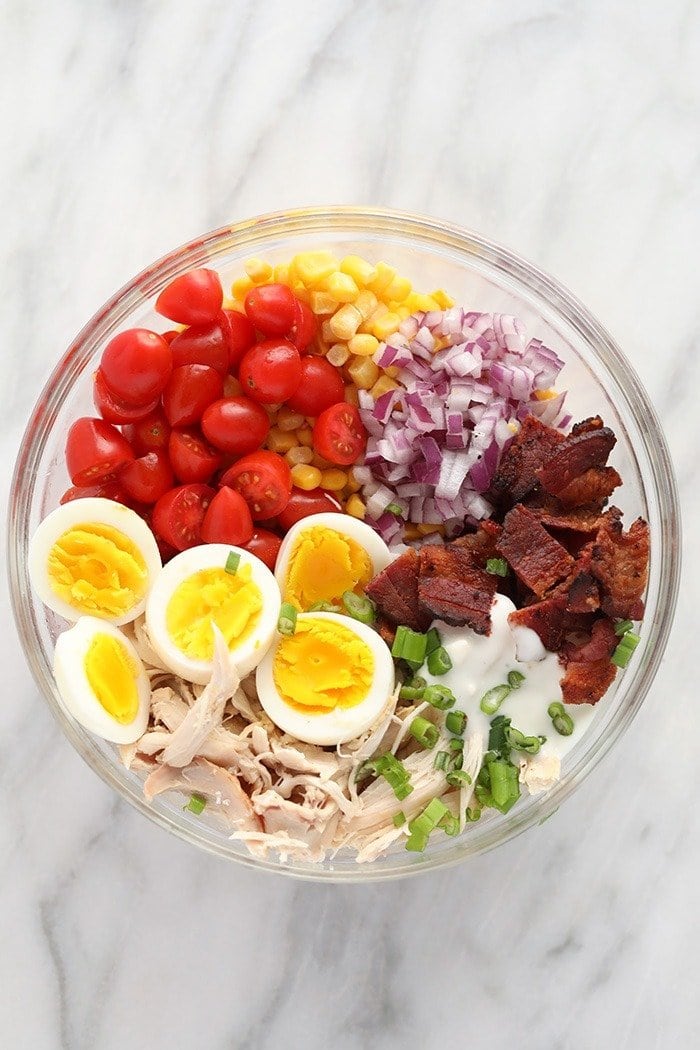 rotisserie chicken cobb salad ingredients in a bowl ready to be mixed