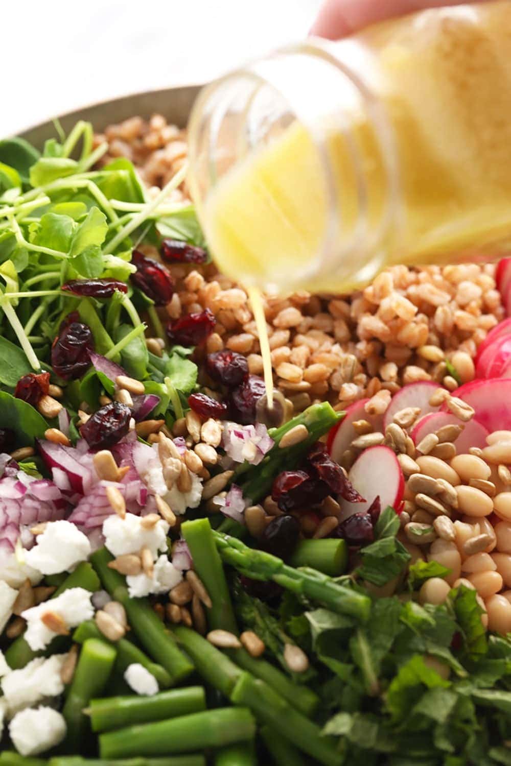 Pouring lemon vinaigrette over the salad 