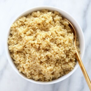 A guide on how to make quinoa served in a white bowl with a gold spoon.