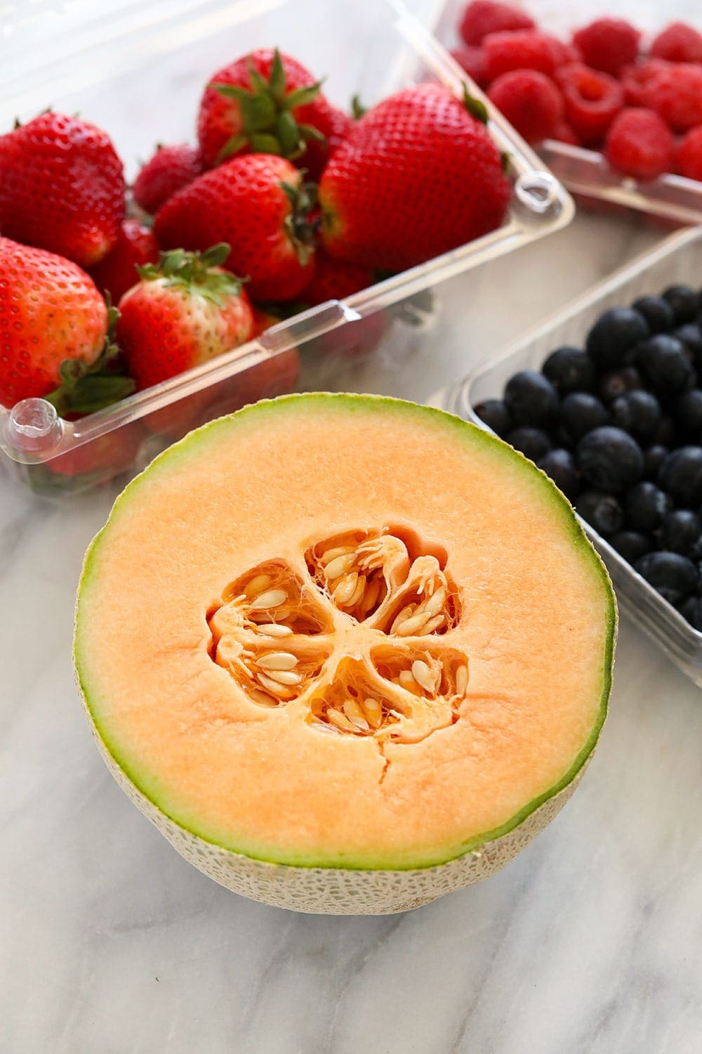 cantaloupe, strawberries and blueberries ready to be used in a fruit salad