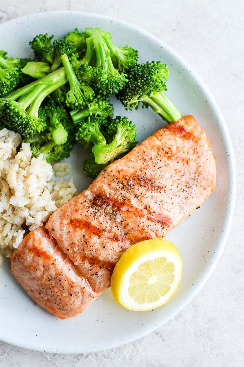 grilled salmon on a plate with broccoli and rice.