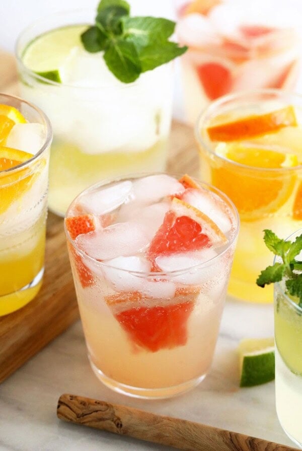 A variety of hard seltzer drinks with ice and mint on a cutting board.