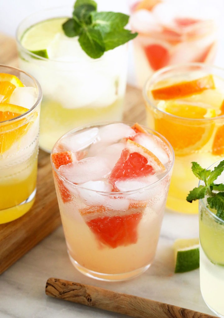 A variety of hard seltzer drinks with ice and mint on a cutting board.