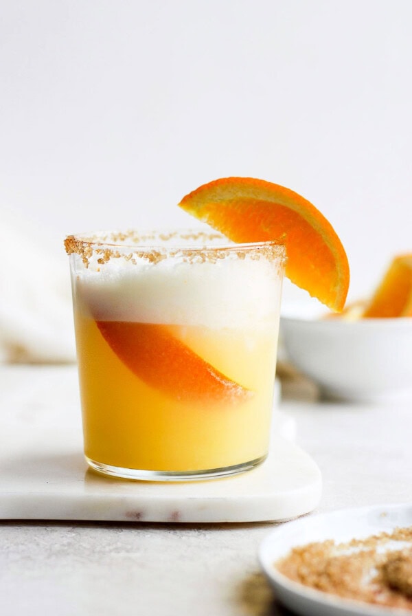 An orange cocktail garnished with a slice of orange.