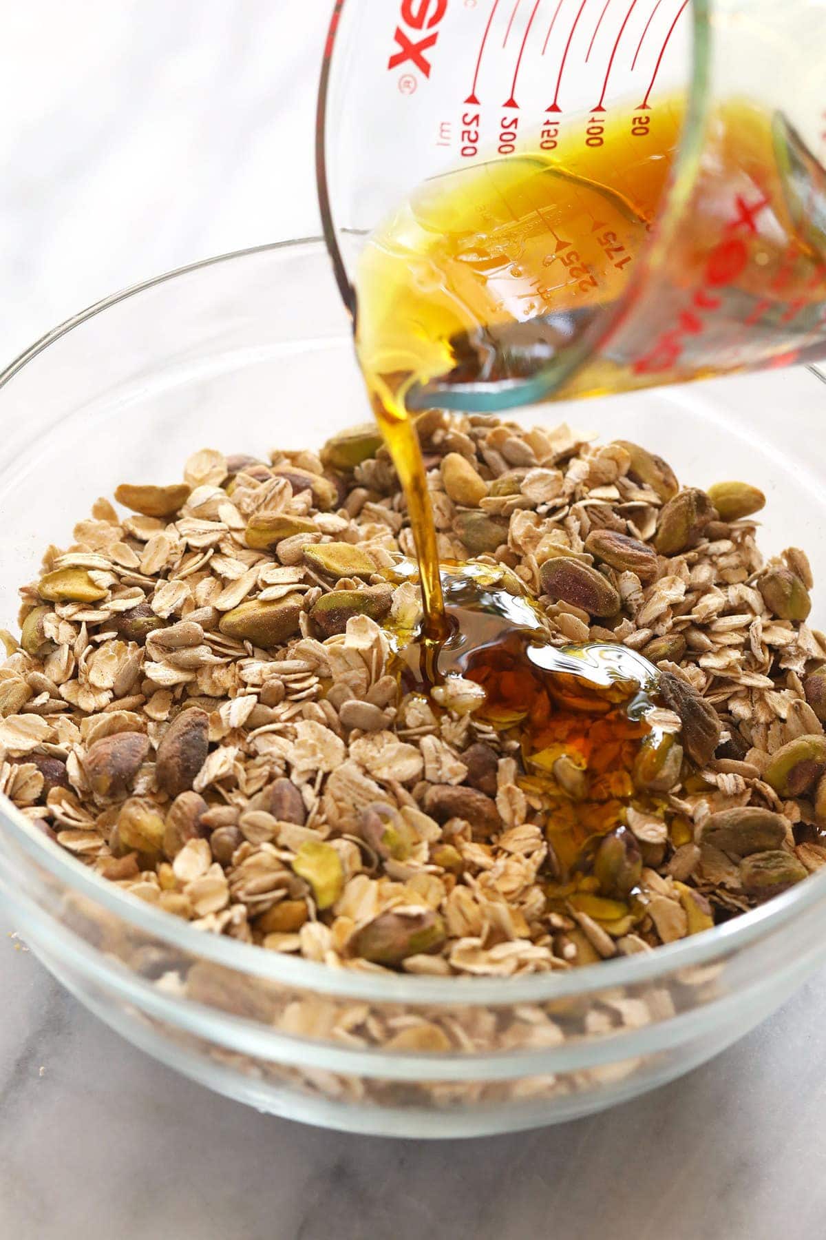 Pouring maple syrup over the granola ingredients. 