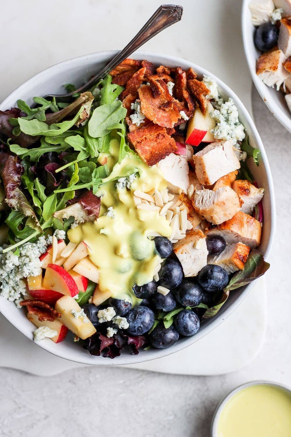 grilled chicken salad in bowl with small cup of dressing.