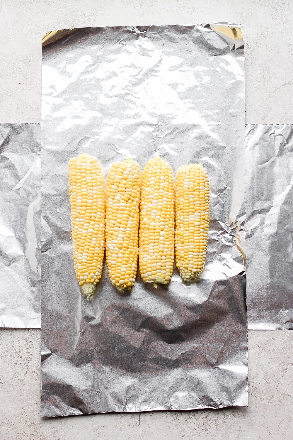 tin foil laid out with 4 ears of corn on it