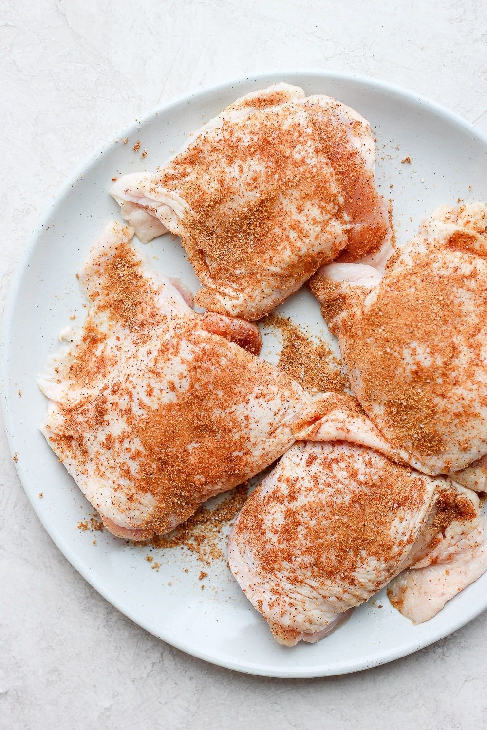 uncooked chicken thighs on plate.