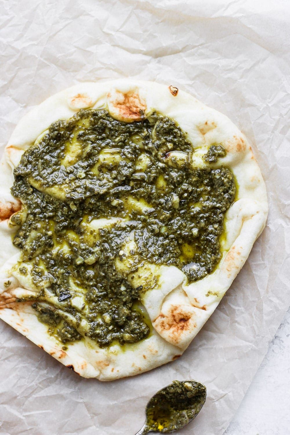 Naan pizza topped with pesto. 