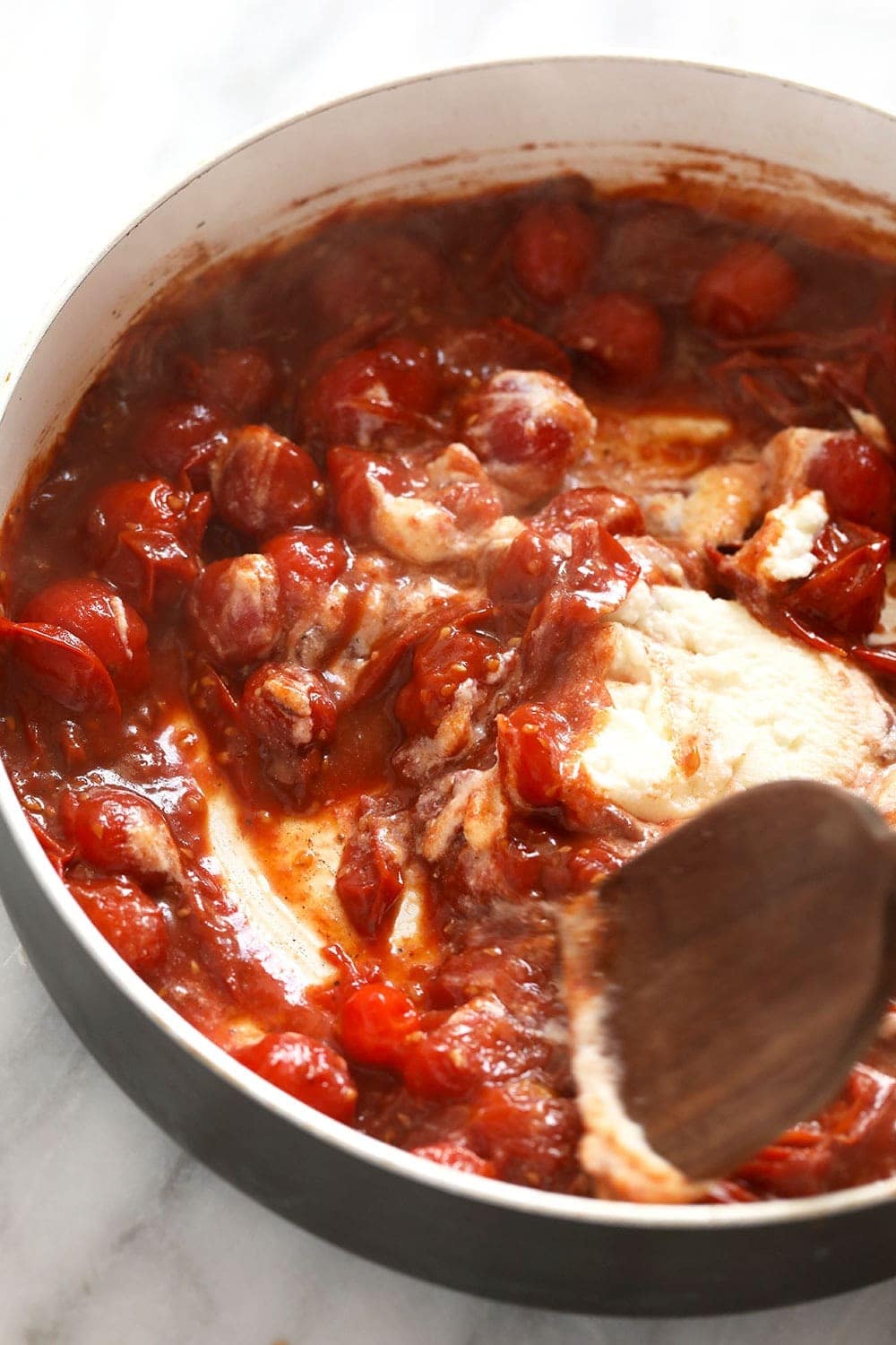 Adding ricotta to a skillet pan to make the tomato sauce creamy. 