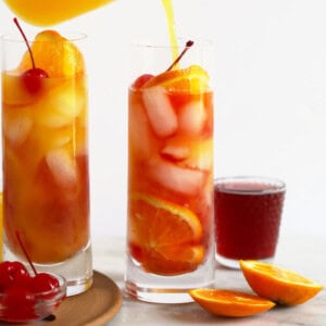 Two glasses of sex on the beach drink being poured into glasses.