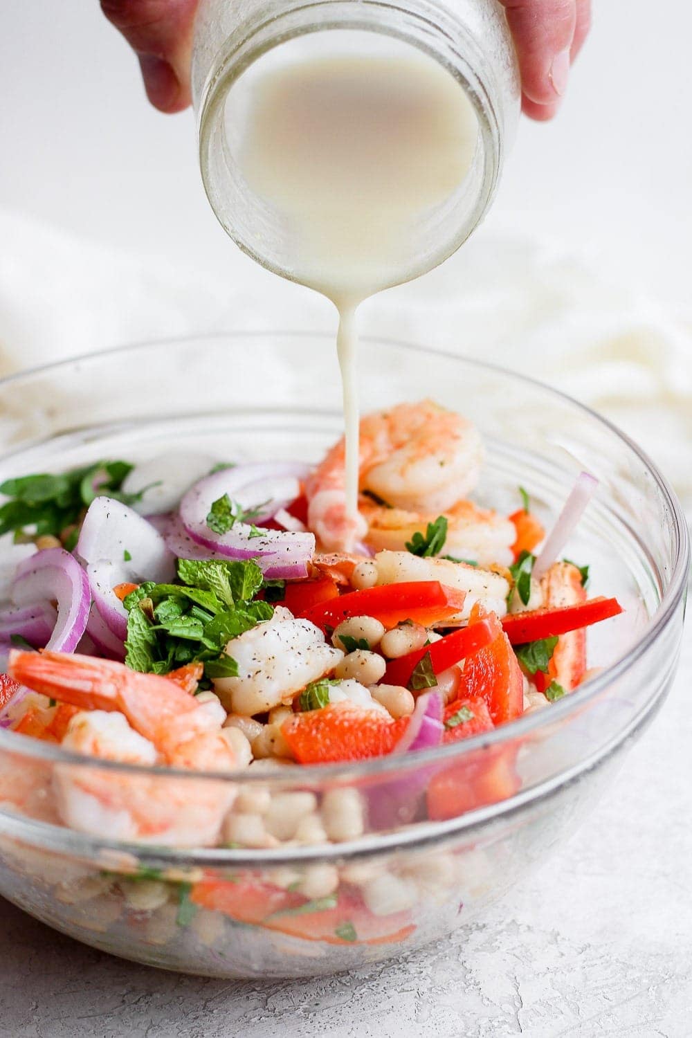 creamy dressing being poured over healthy shrimp salad