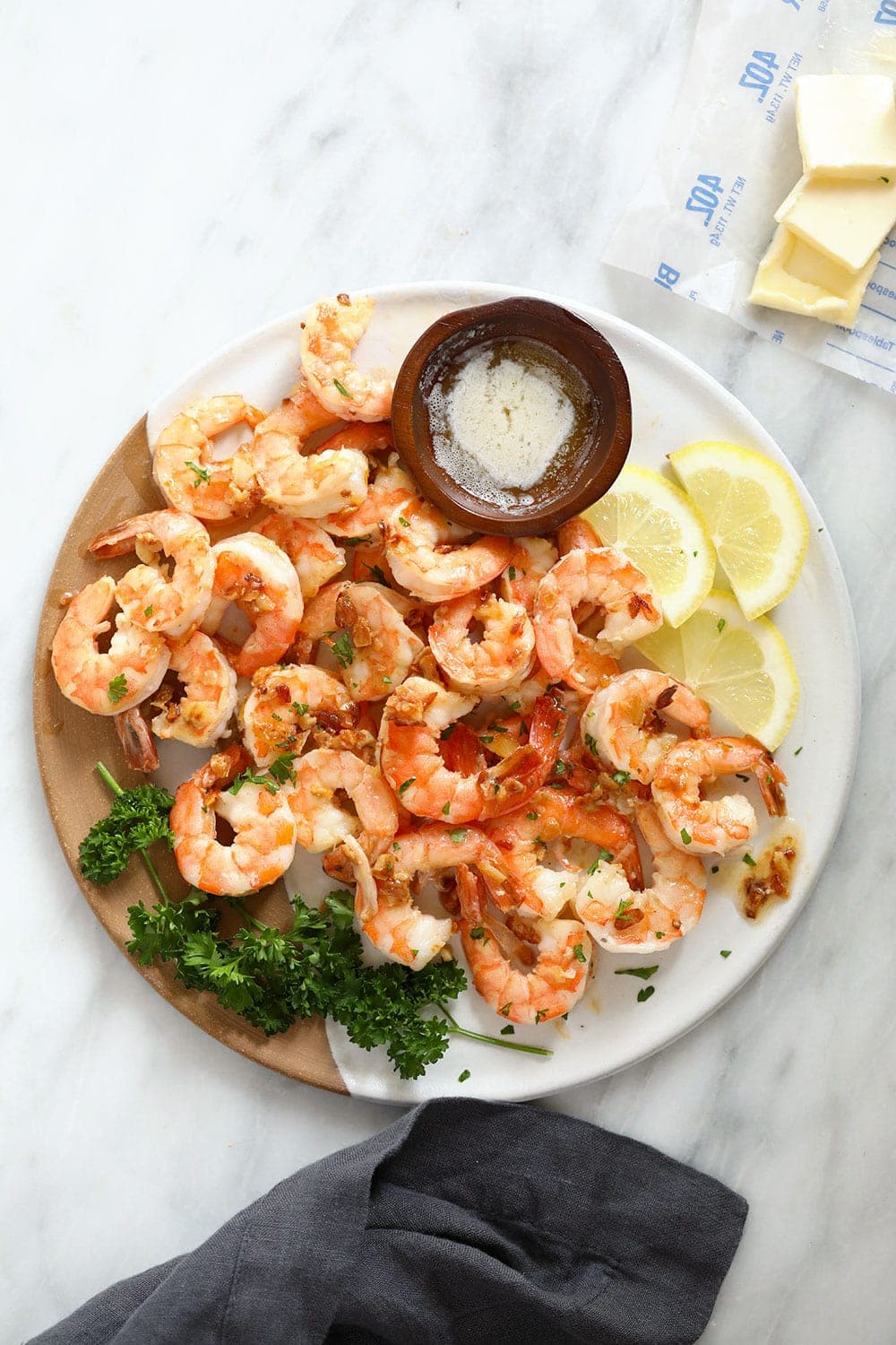 garlic butter shrimp on a plate with fresh lemon slices