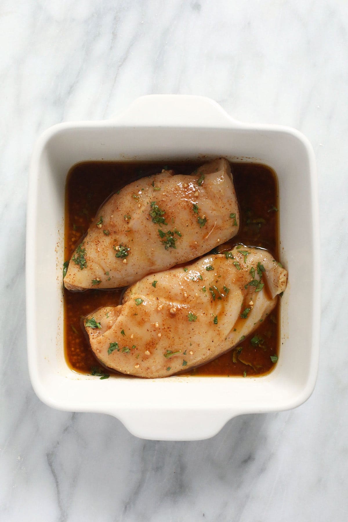 Chicken marinating in a casserole dish. 