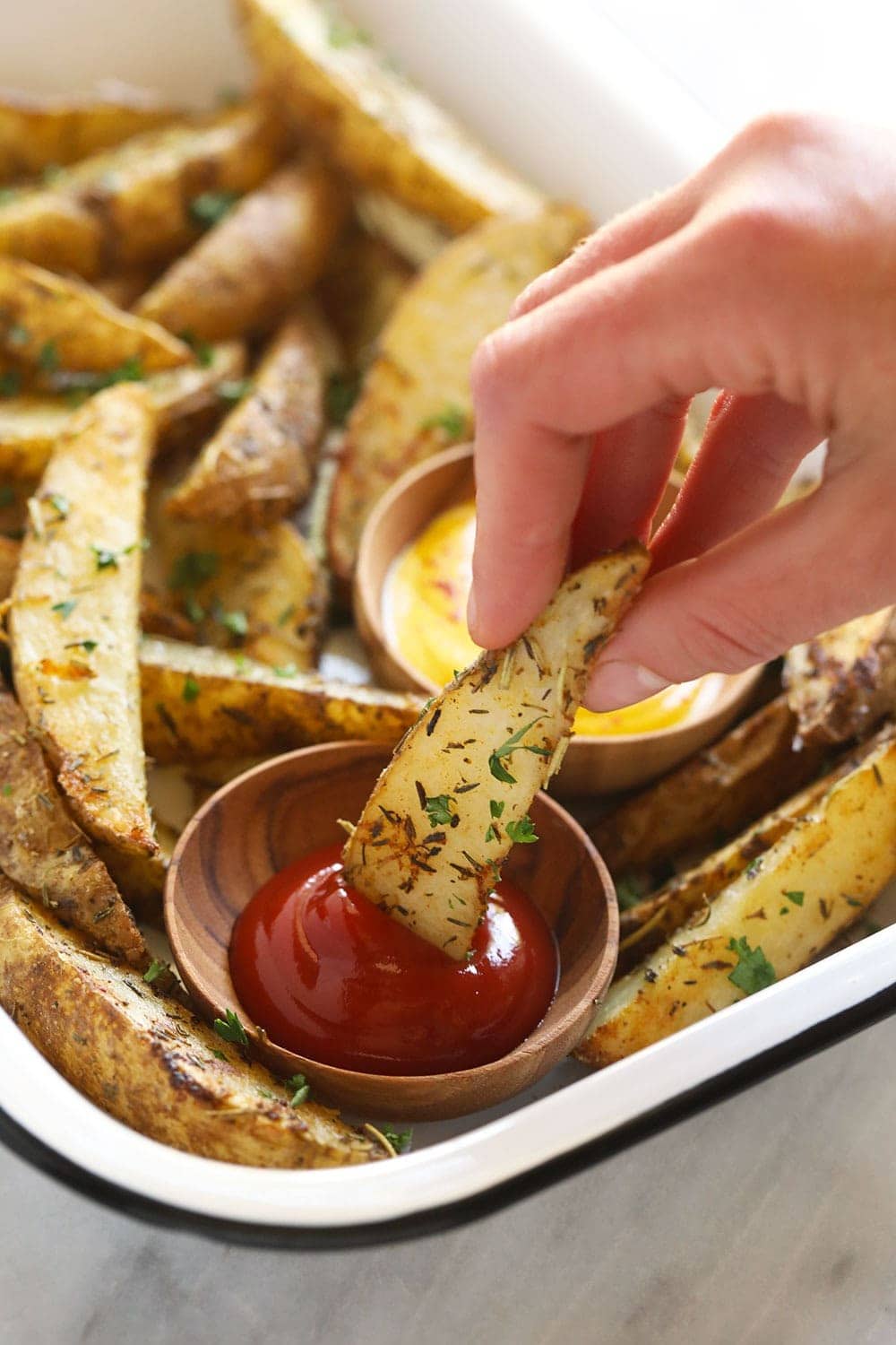 Dipping a potato wedge into ketchup.