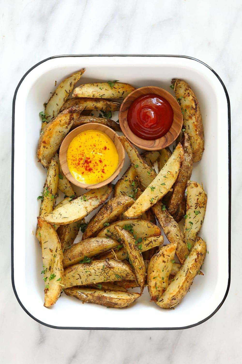 Potato wedges in a platter with ketchup and mustard. 