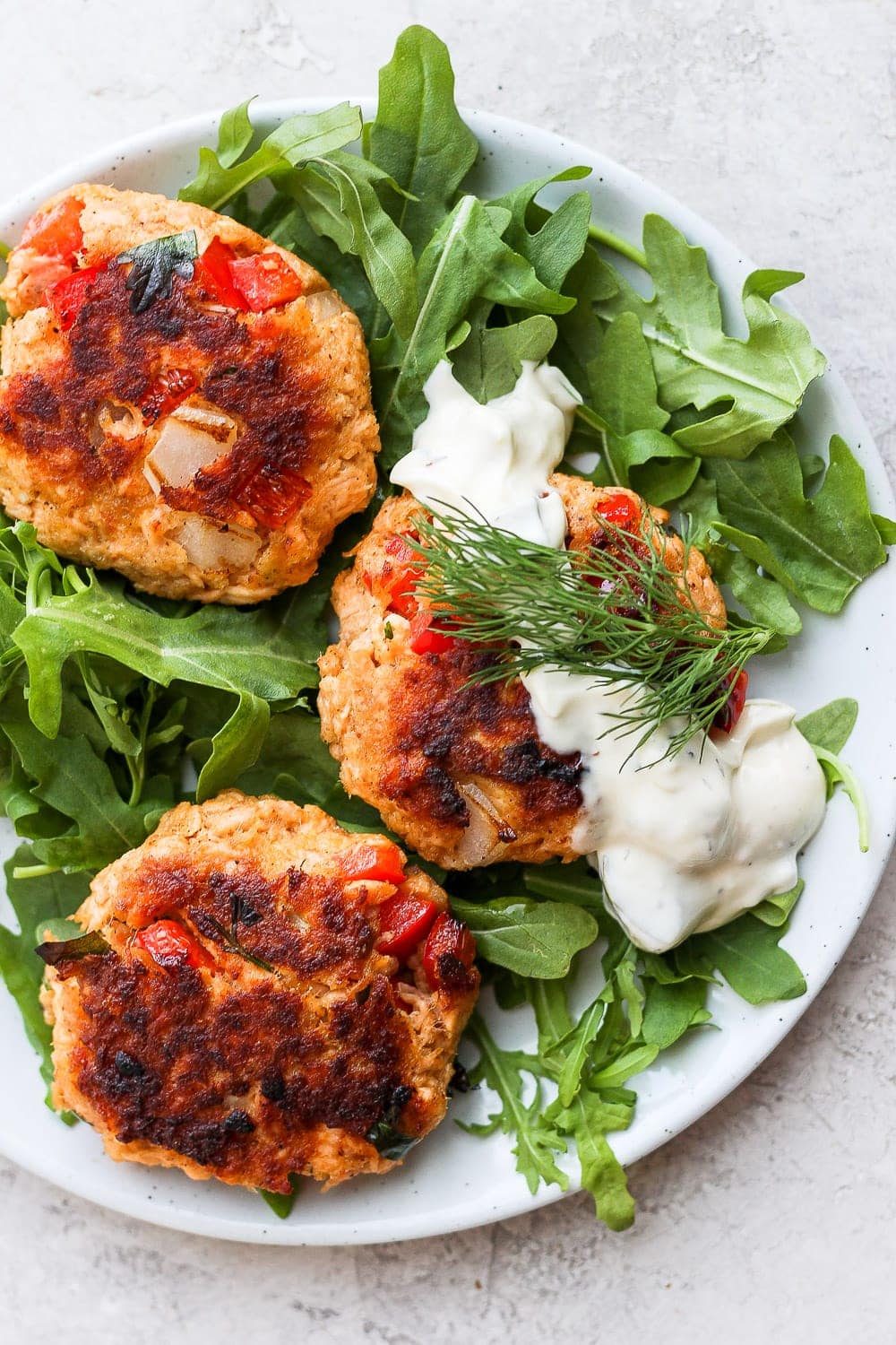 salmon patties atop arugula with tartar sauce