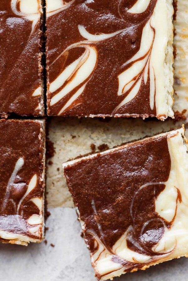 a slice of chocolate swirl cheesecake bars on top of a piece of paper.