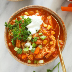 a bowl of buffalo chicken chili with sour cream and carrots.