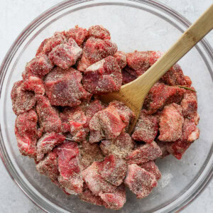 Instant pot shredded beef stew in a glass bowl with a wooden spoon.