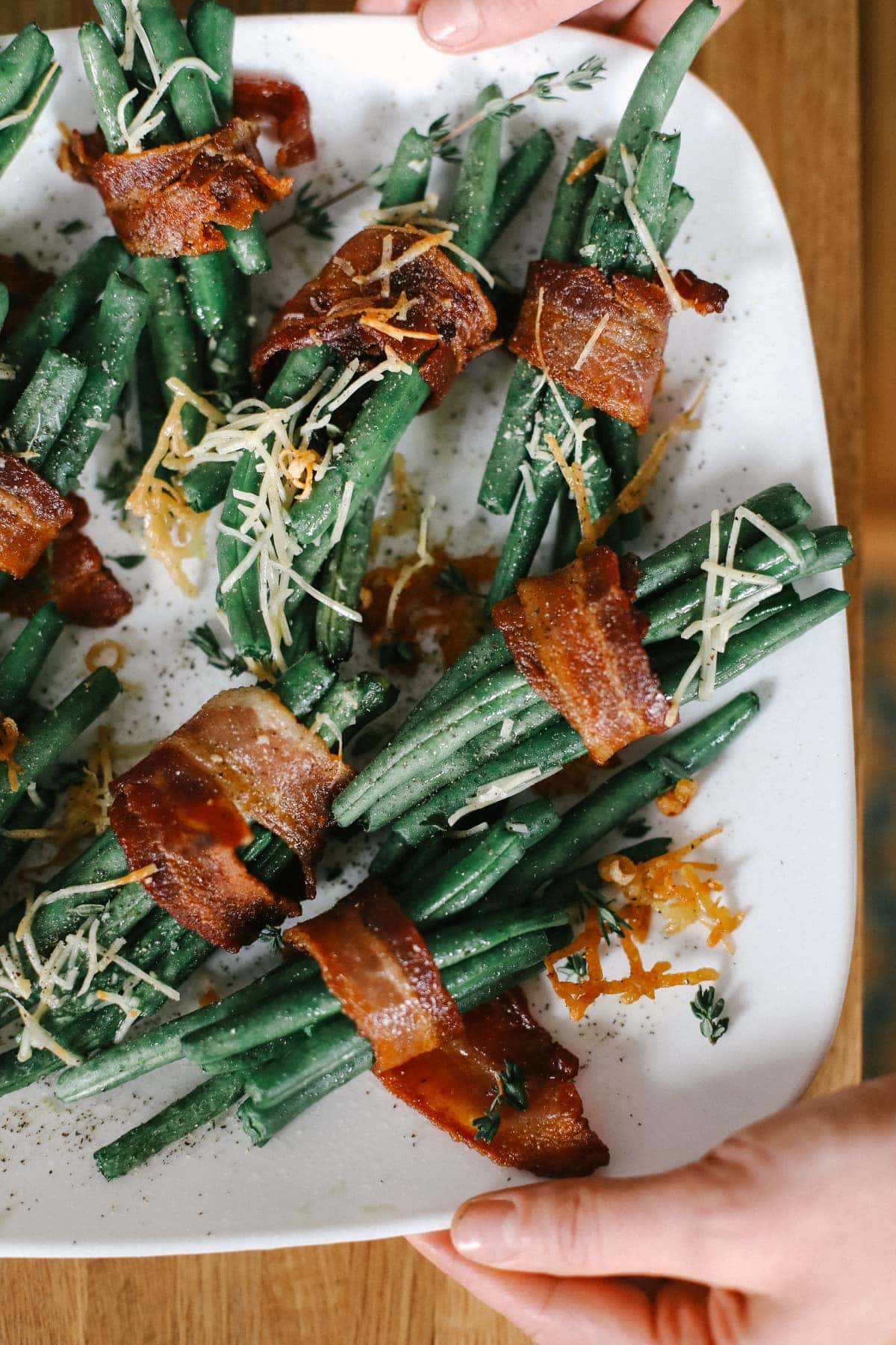 bacon wrapped green beans on a plate topped with parmesan cheese