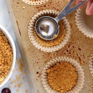 a person pouring granola into a muffin tin.