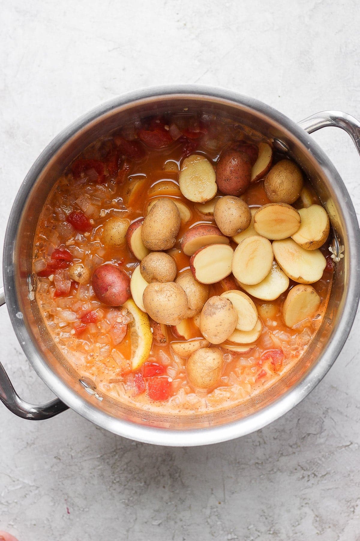 potatoes being added to a seafood boil broth