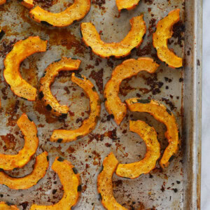 Delicata squash roasted on a baking sheet.