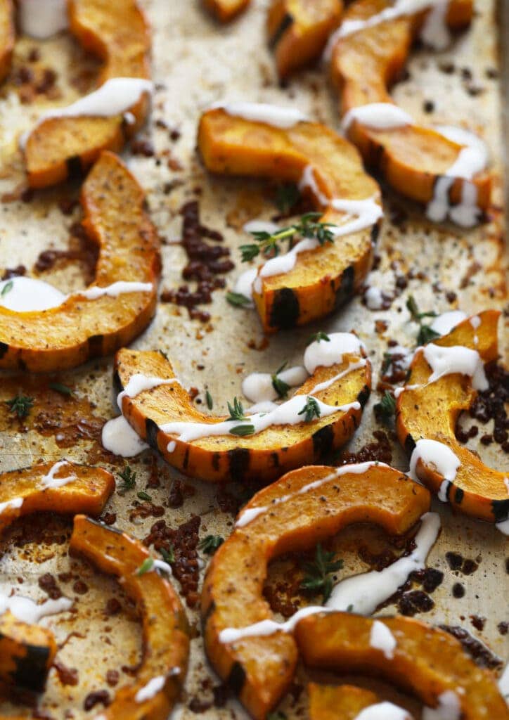 delicata squash with a creme fresh drizzle on a roasting pan