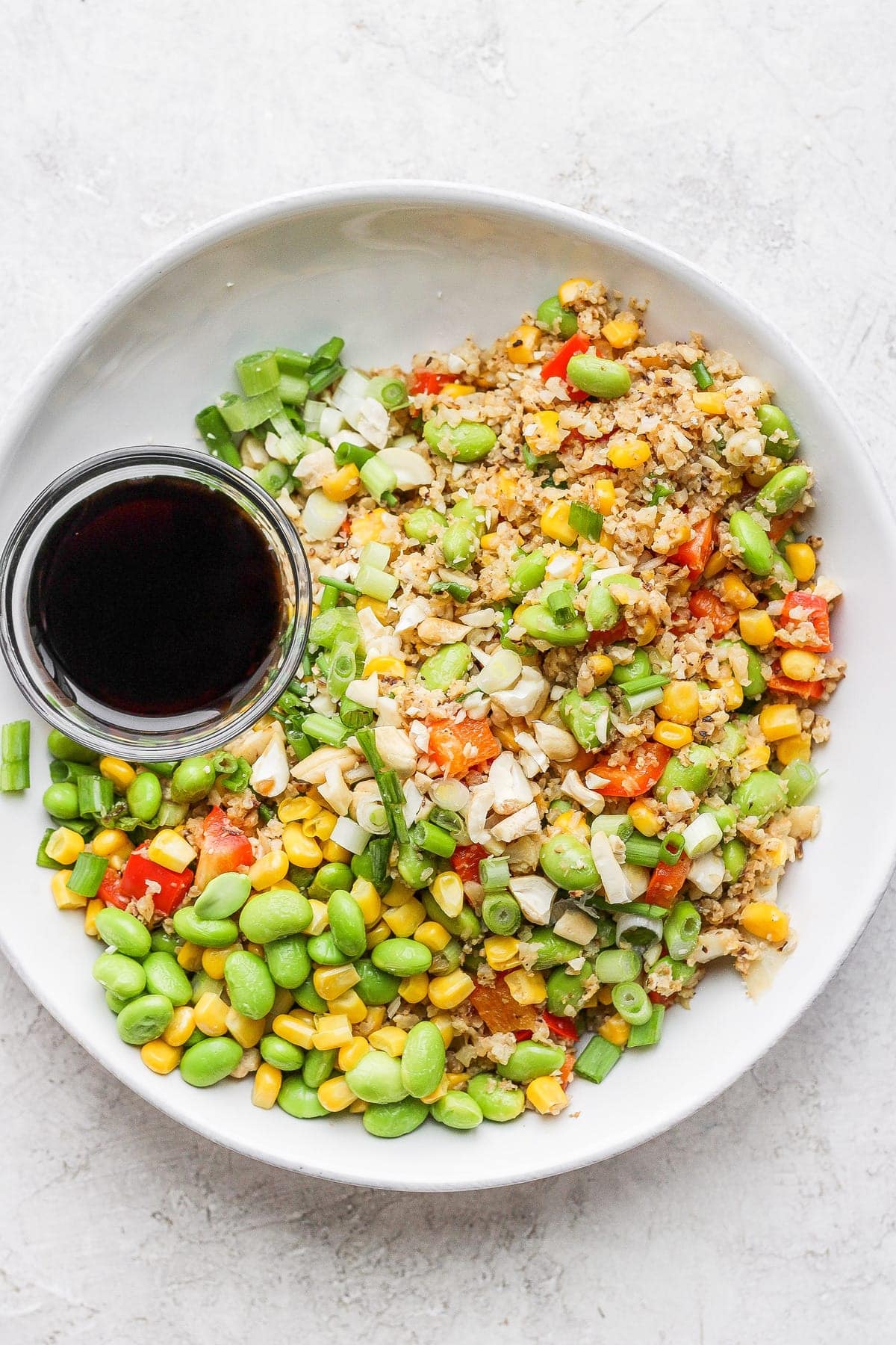 cauliflower fried rice in a bowl next to the sauce