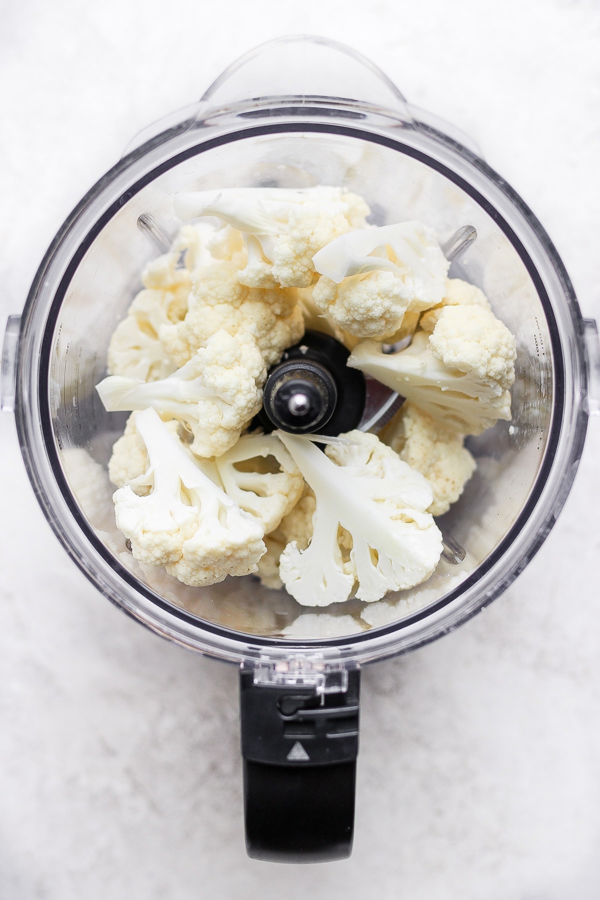 Raw florets of cauliflower in a food processor. 