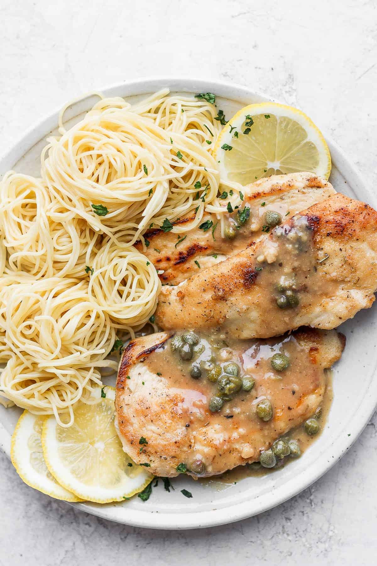 Chicken piccata on a plate with angel hair pasta. 