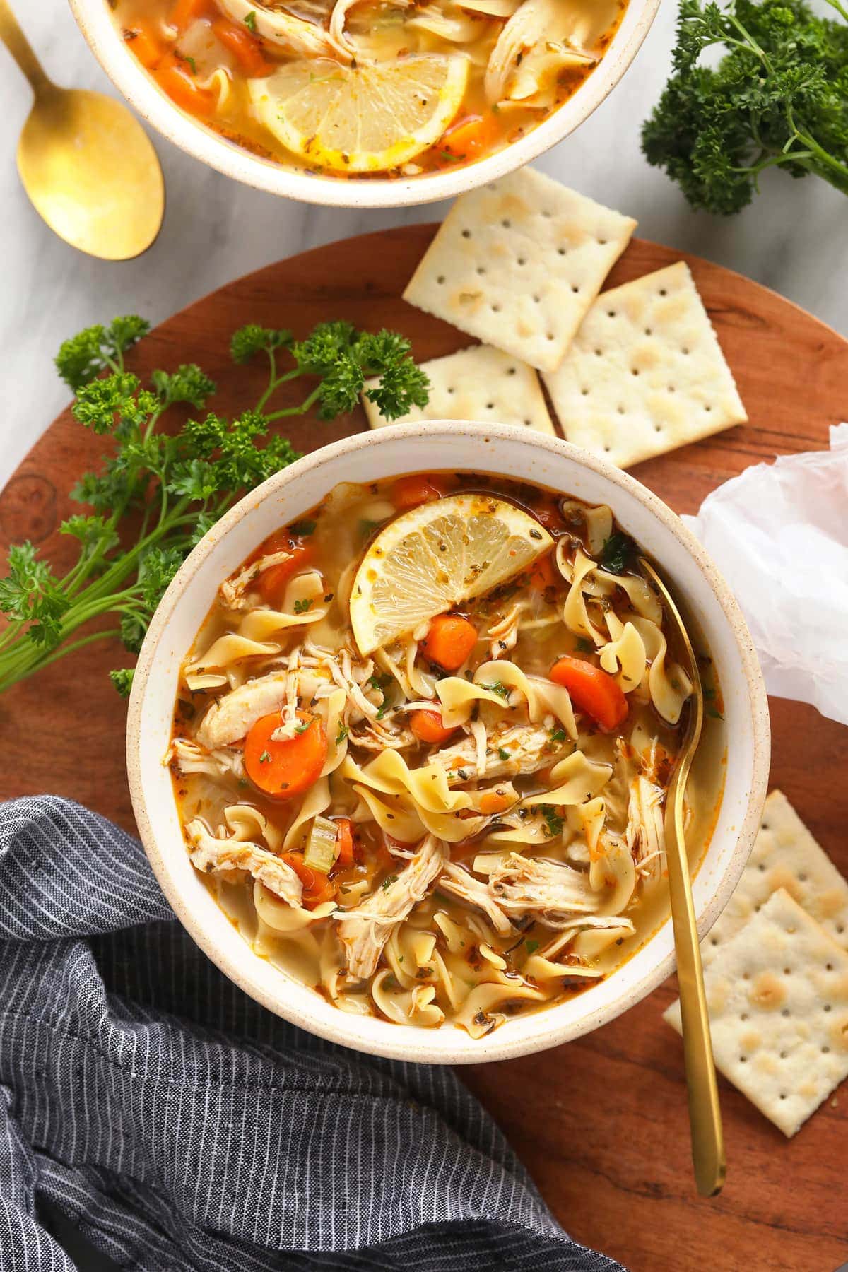 chicken noodle soup in bowl with spoon and crackers