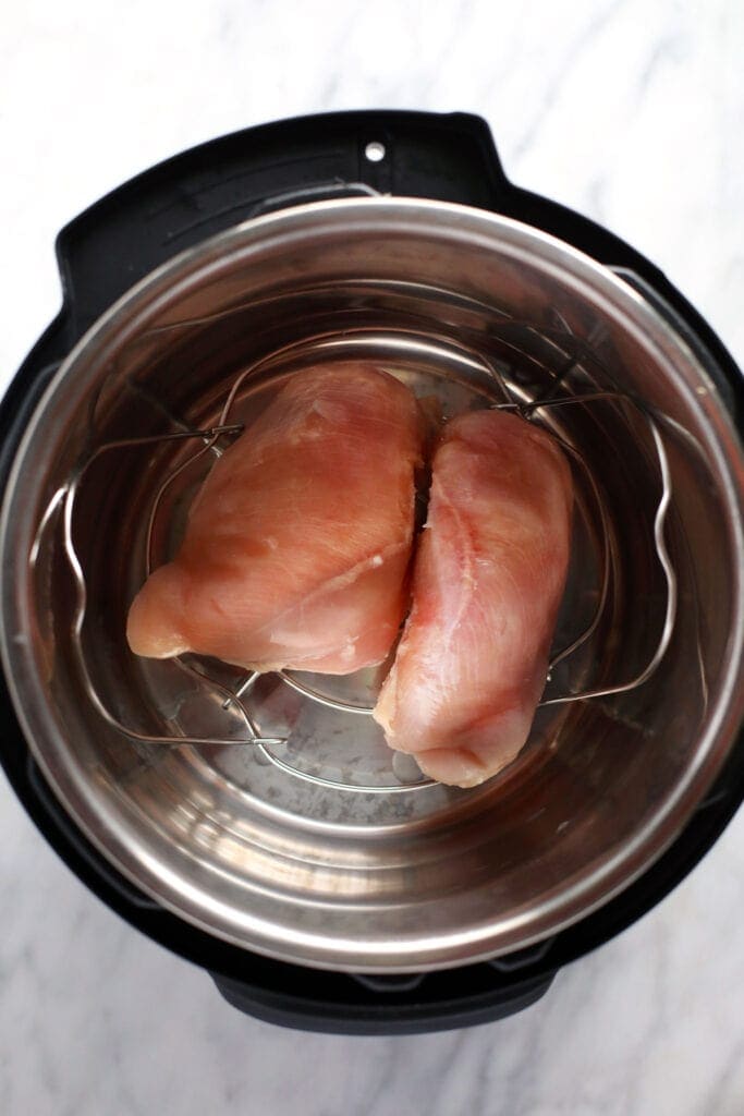 raw chicken breasts in the instant pot ready to be cooked and then shredded.