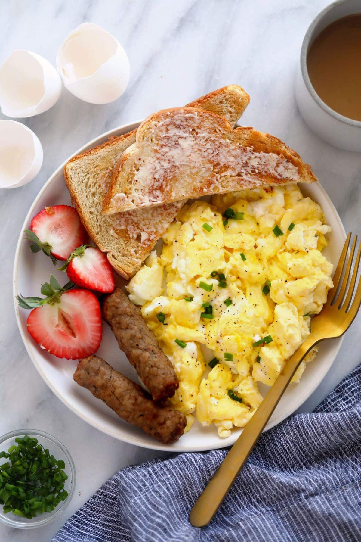 scrambled eggs on a plate with fresh fruit and toast