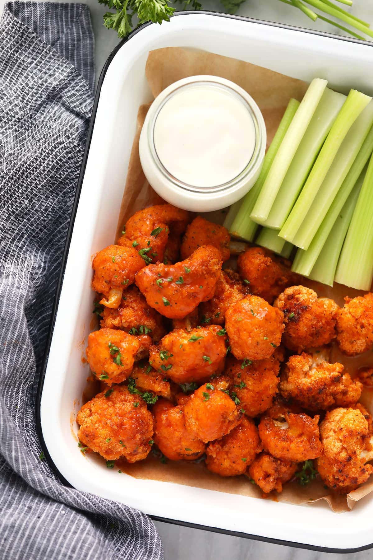 air fryer buffalo cauliflower in container with blue cheese dip and celery