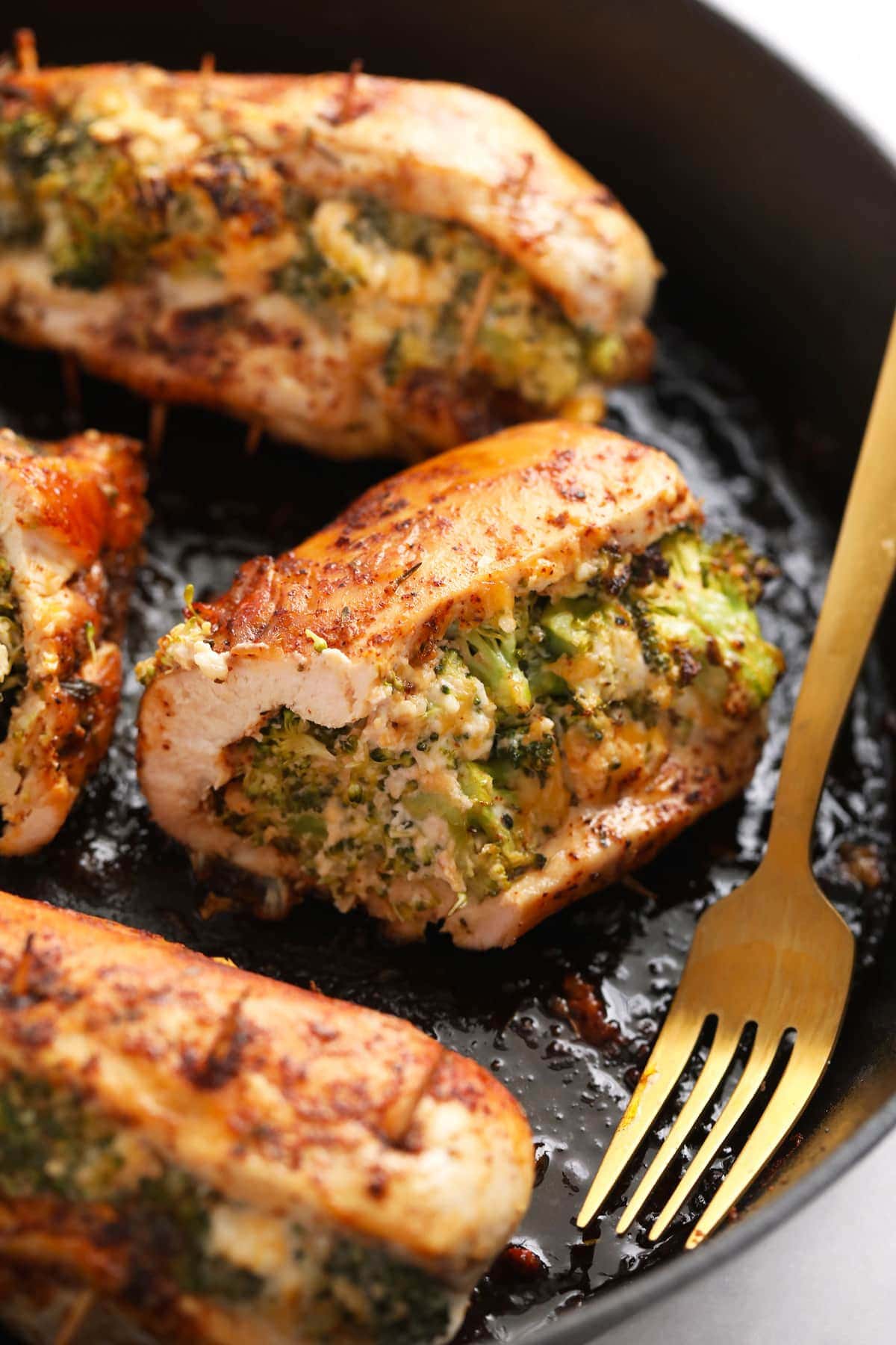 broccoli and cheese stuffed chicken breast in a cast iron skillet.