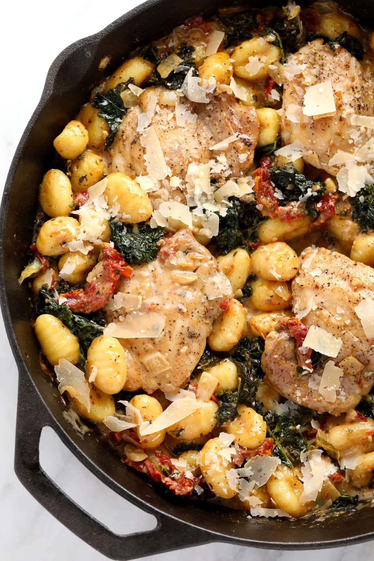 creamy tuscan chicken and gnocchi in a cast iron skillet ready to be served