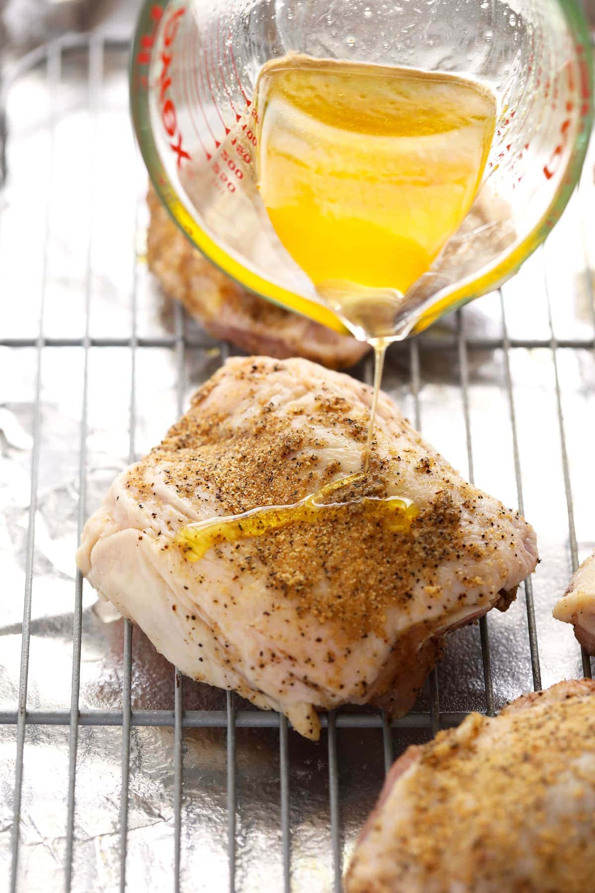 Pouring oil on top of chicken thighs. 