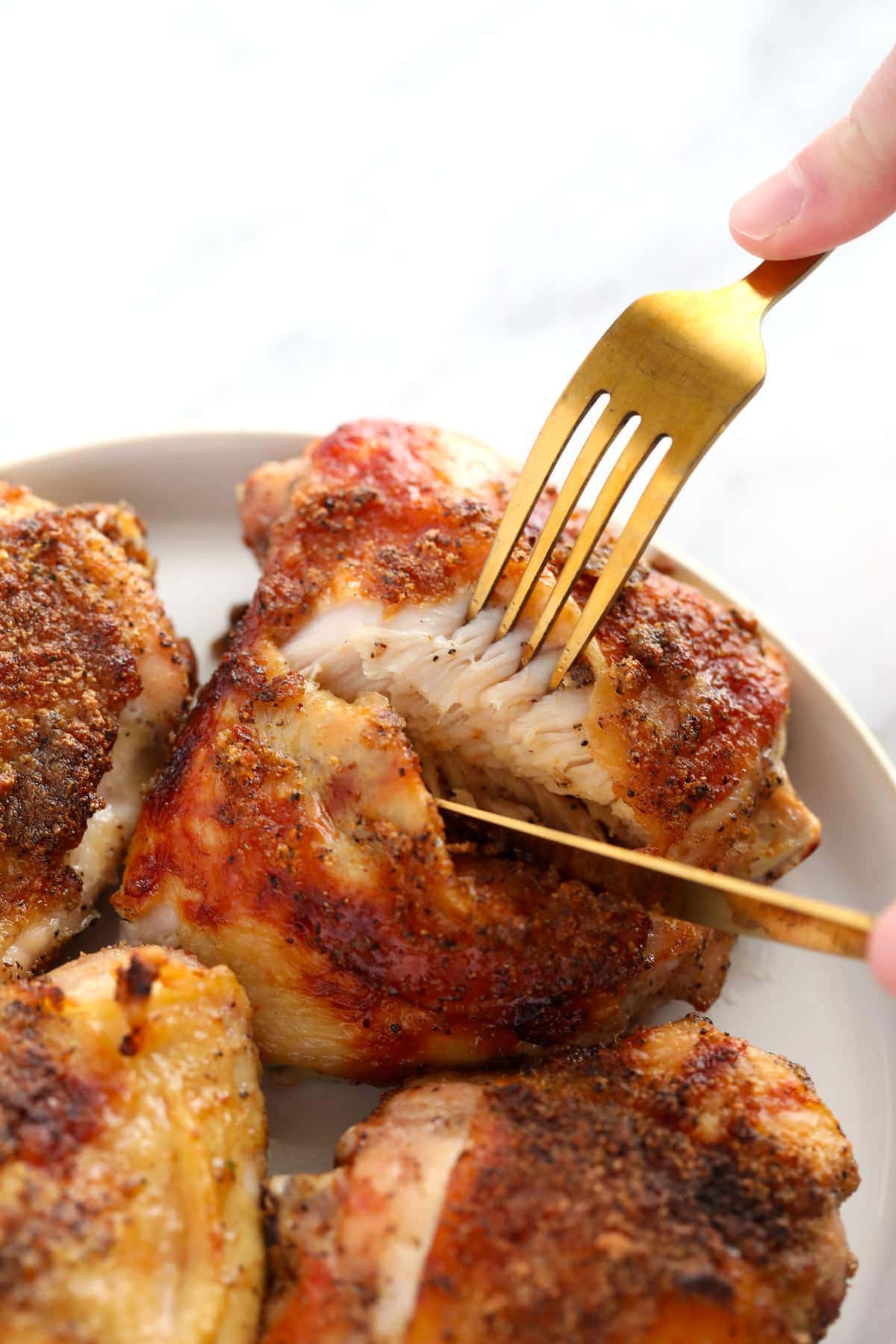 Cutting through a chicken thigh on a plate. 