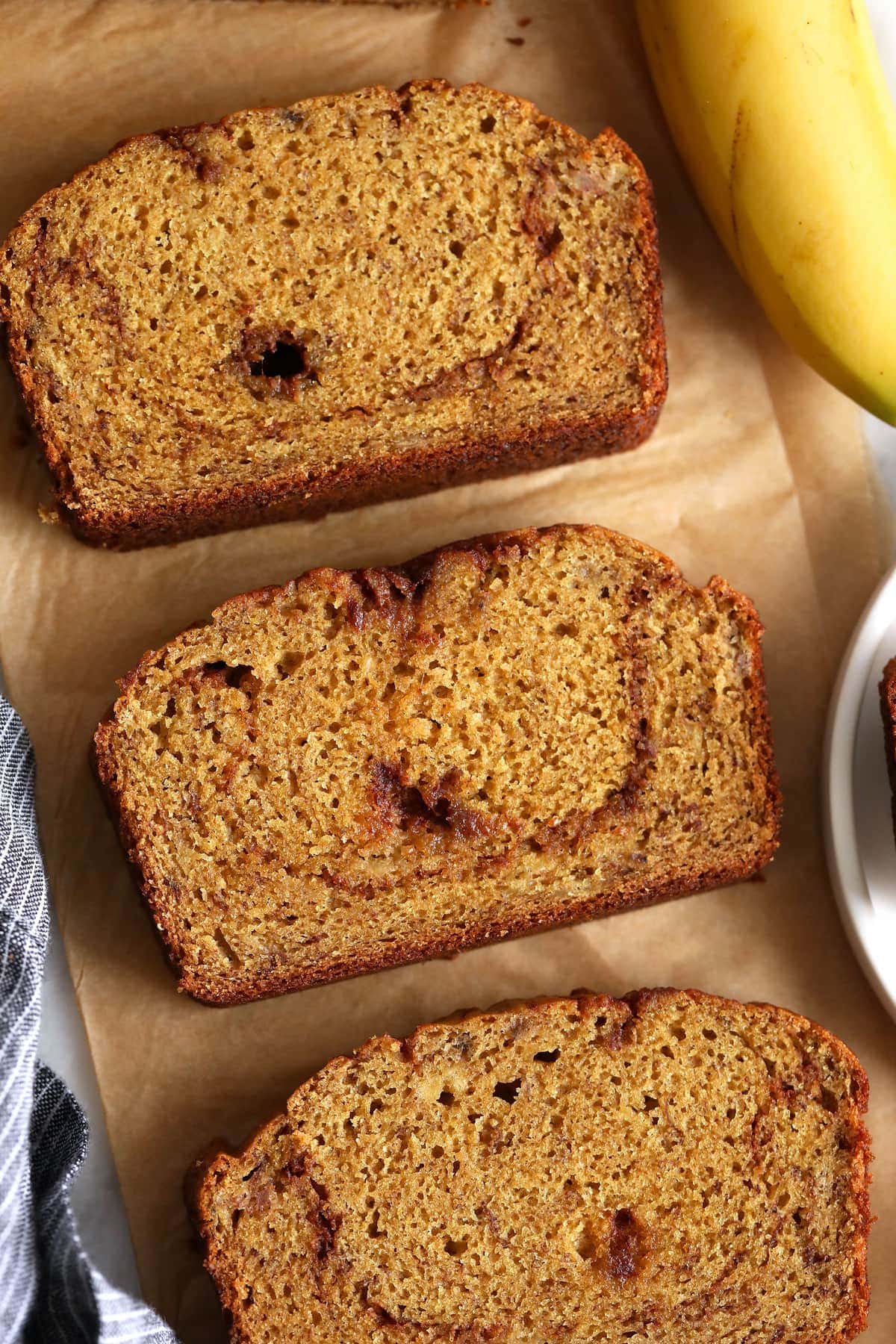 Cinnamon swirl banana bread slices on parchment paper. 