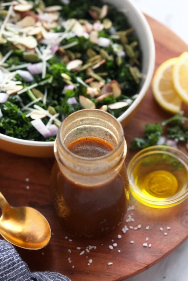 Homemade kale salad with dressing on a wooden board.