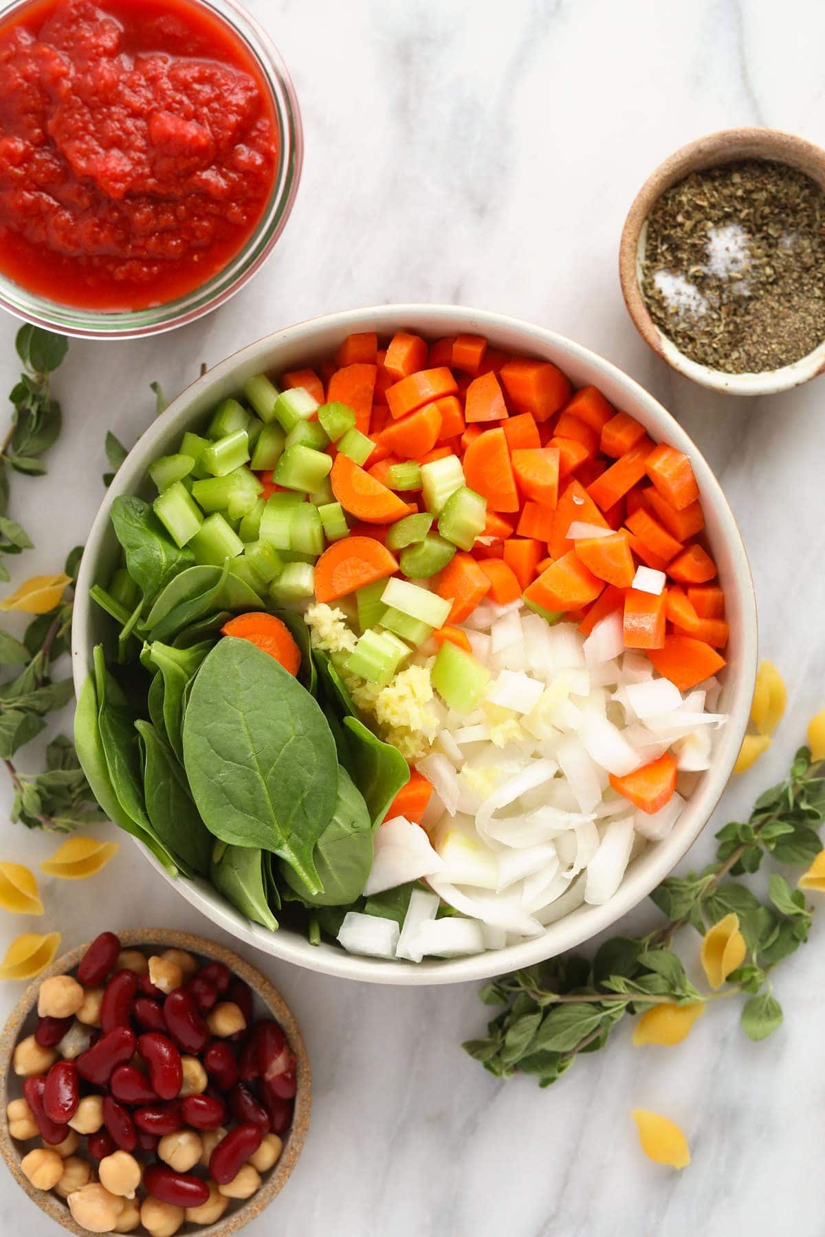 A bowl of carrots, celery, onion, garlic, and spinach. 