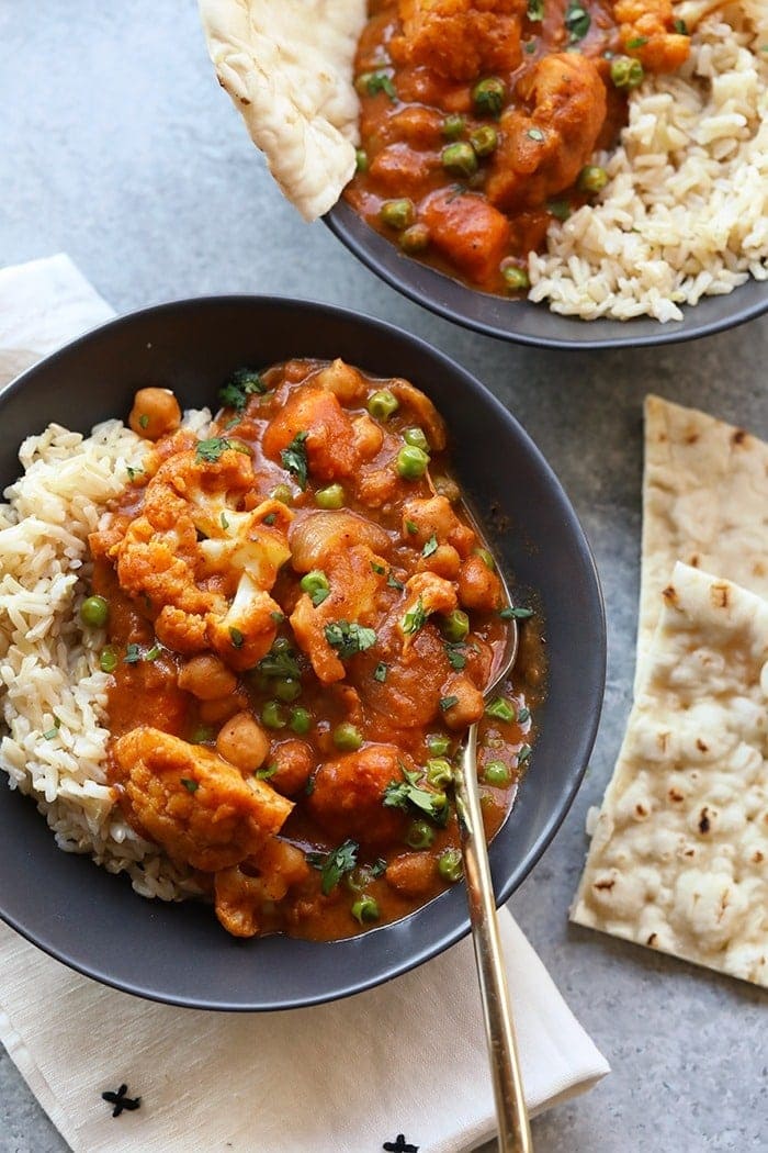 a bowl of chicken curry with rice and naan.