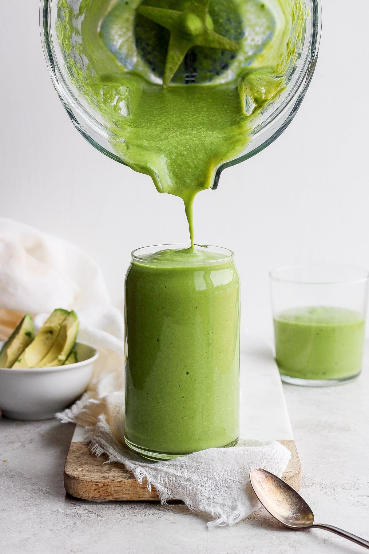 avocado smoothie being poured from a blender to a glass