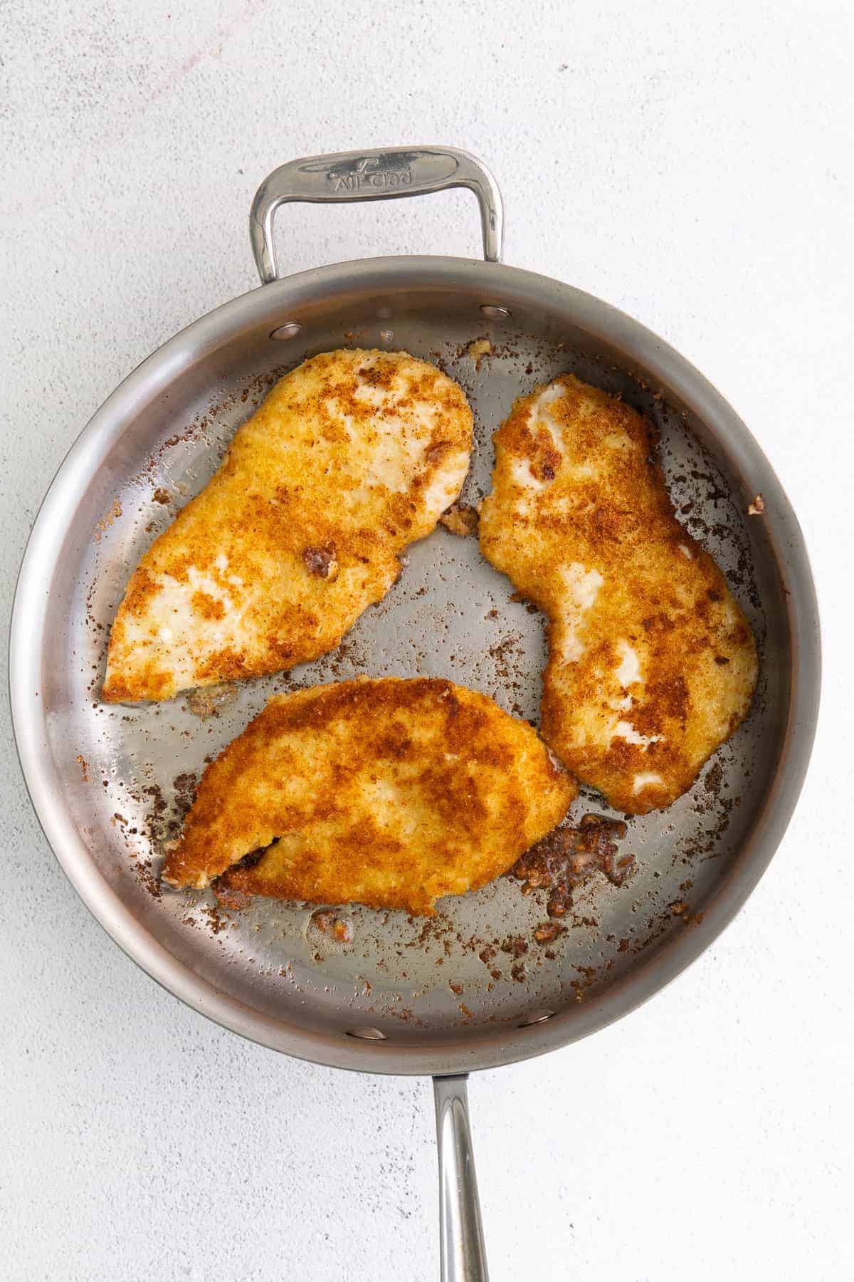 parmesan crusted chicken in frying pan.