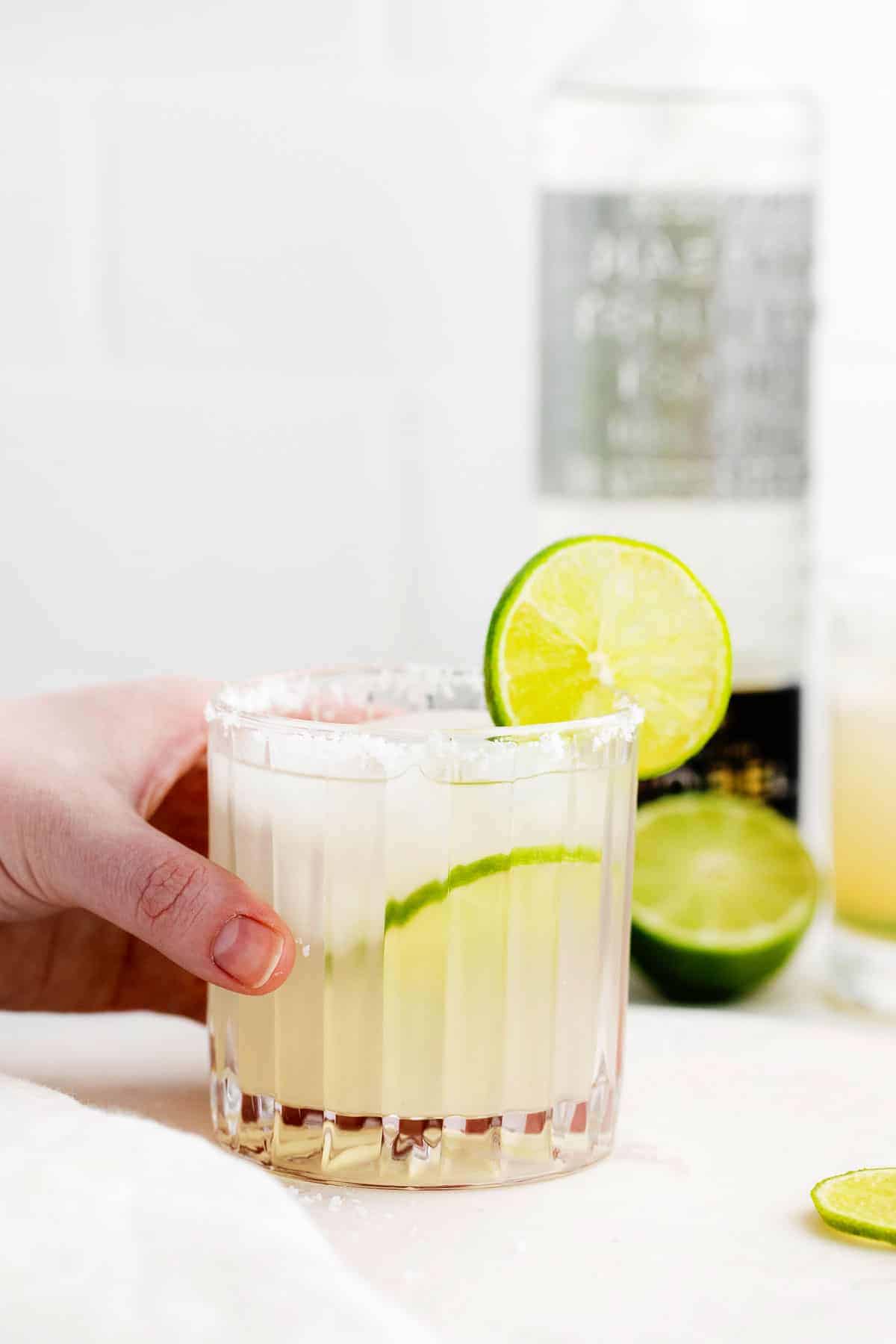 A glass of margarita with a fresh lime slices on the glass. 